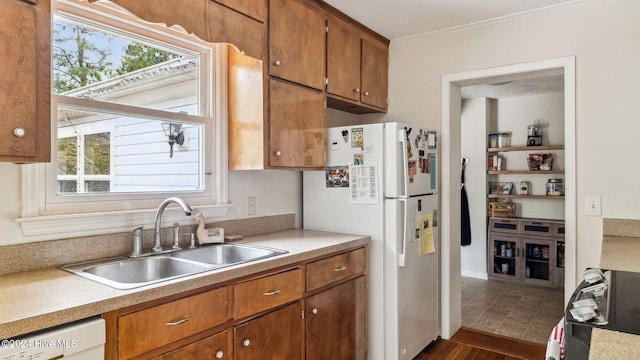 kitchen featuring white appliances, brown cabinets, a sink, light countertops, and a wealth of natural light