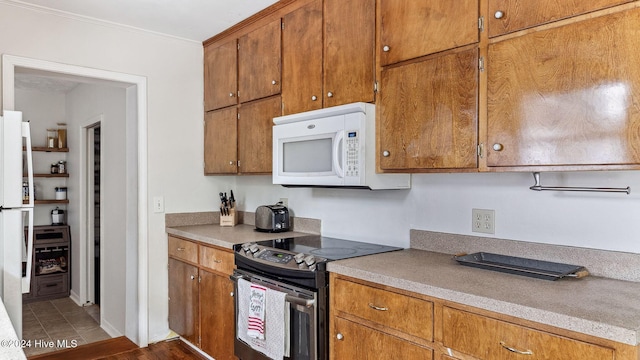 kitchen with brown cabinets, white appliances, light countertops, and crown molding