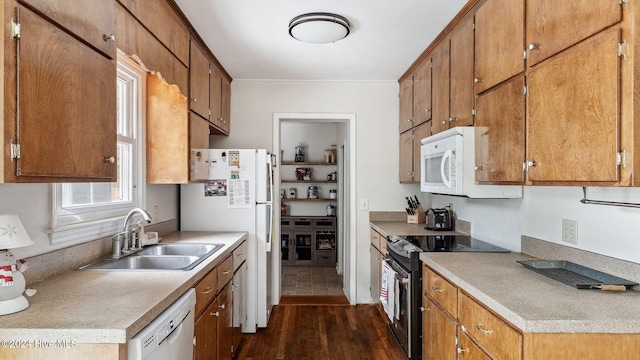 kitchen with light countertops, white appliances, a sink, and brown cabinets