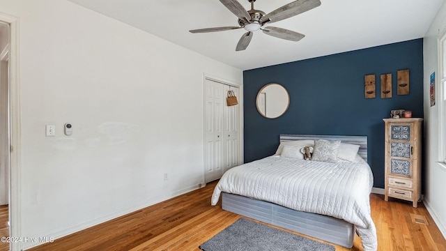 bedroom featuring a ceiling fan, a closet, baseboards, and light wood finished floors