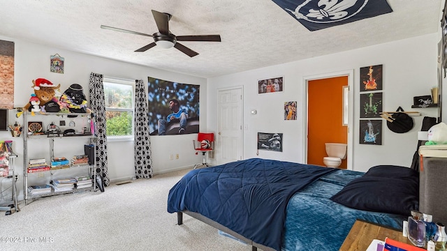 carpeted bedroom with ensuite bath, baseboards, ceiling fan, and a textured ceiling