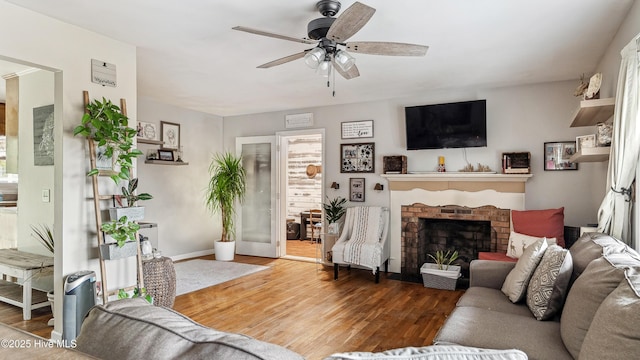 living area featuring a fireplace, wood finished floors, a ceiling fan, and baseboards