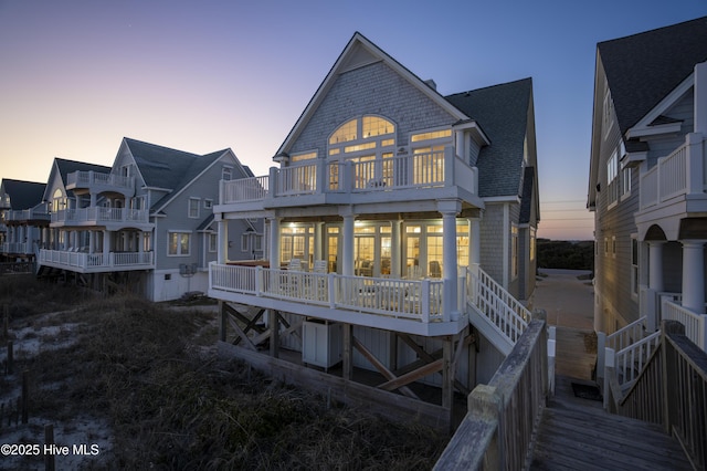 rear view of property with a shingled roof and stairs