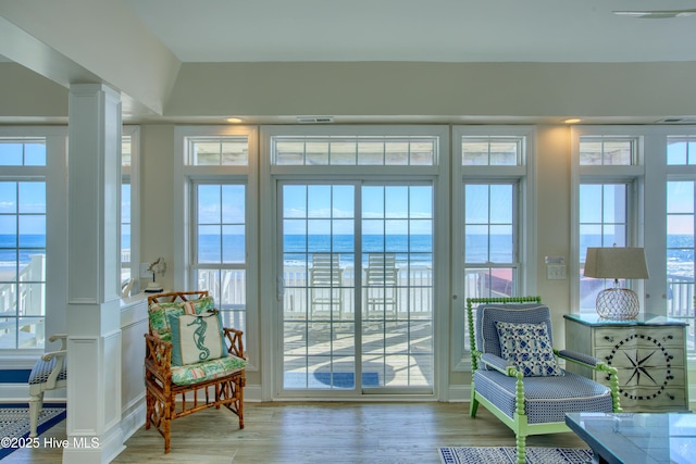 sunroom with visible vents, a water view, decorative columns, and a wealth of natural light