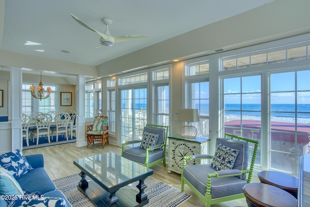 sunroom with ceiling fan with notable chandelier, a water view, and visible vents