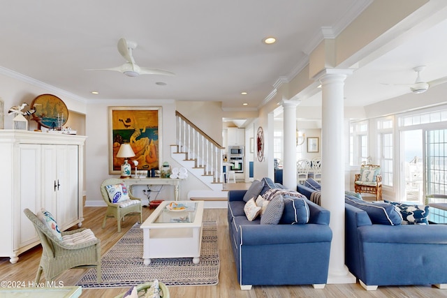 living room featuring light wood-type flooring, decorative columns, stairway, and ceiling fan