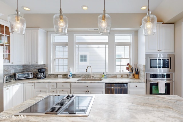 kitchen featuring glass insert cabinets, plenty of natural light, appliances with stainless steel finishes, and a sink