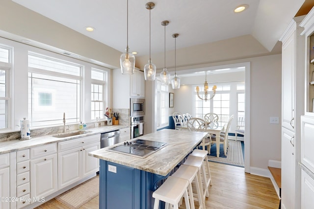 kitchen featuring stainless steel appliances, a breakfast bar, a kitchen island, a sink, and white cabinets