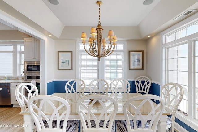 dining area with a chandelier, visible vents, and light wood-style floors