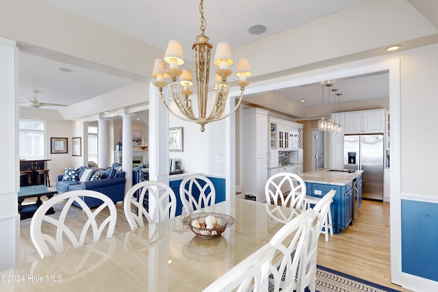 dining space with a fireplace, decorative columns, recessed lighting, light wood-style flooring, and ceiling fan with notable chandelier