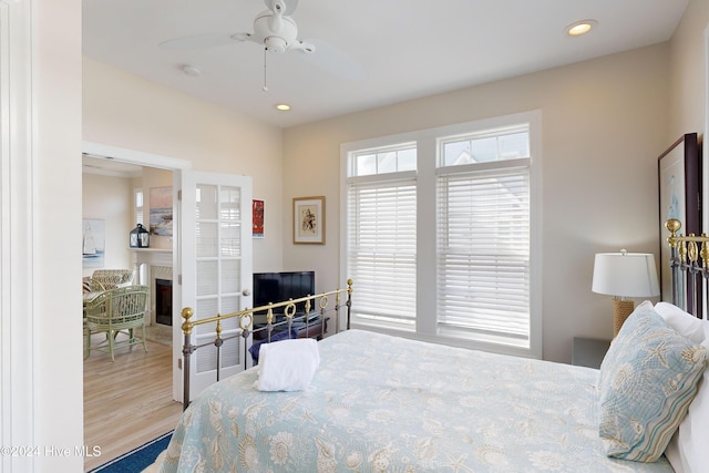 bedroom featuring ceiling fan, a fireplace, wood finished floors, and recessed lighting