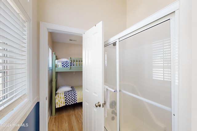 full bathroom with wood finished floors, a shower stall, and visible vents