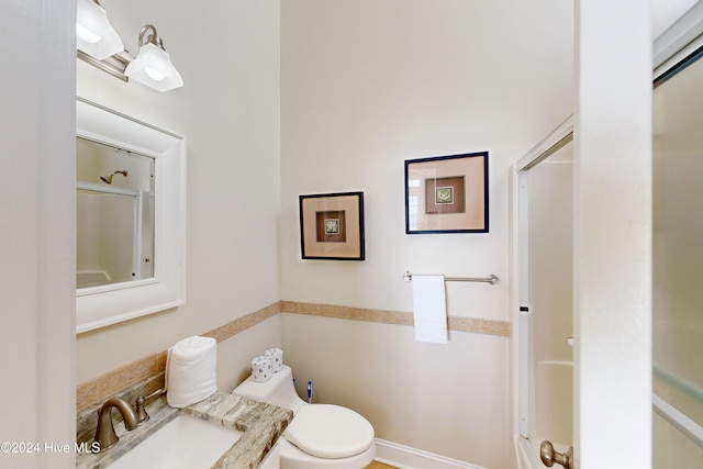 bathroom featuring toilet, an enclosed shower, and vanity