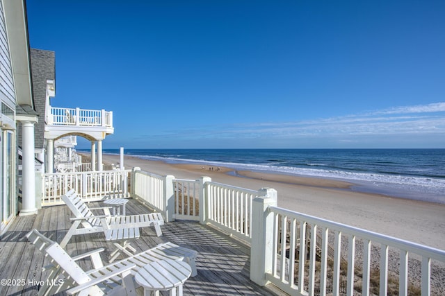 wooden deck featuring a view of the beach and a water view