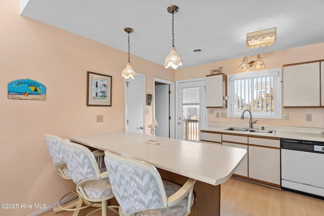 kitchen featuring a kitchen bar, white dishwasher, white cabinets, and sink