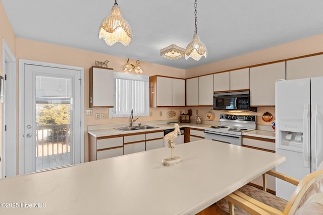 kitchen featuring white appliances, a kitchen breakfast bar, sink, hanging light fixtures, and a wealth of natural light