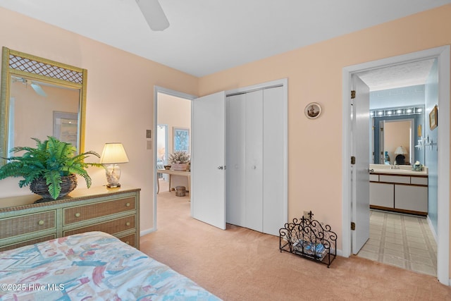 carpeted bedroom with a closet, ensuite bath, and ceiling fan