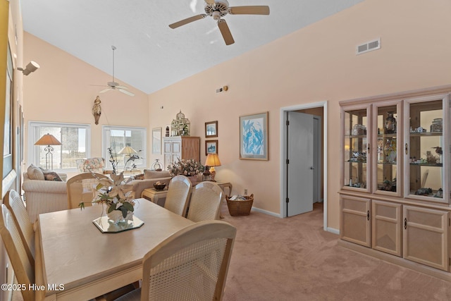 dining area with light carpet, high vaulted ceiling, and ceiling fan