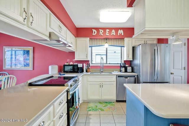 kitchen featuring sink, white cabinets, stainless steel appliances, and light tile patterned floors