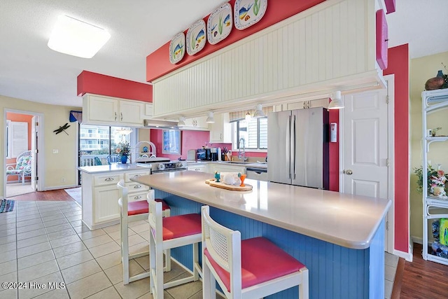 kitchen featuring a kitchen breakfast bar, a center island, white cabinets, and appliances with stainless steel finishes