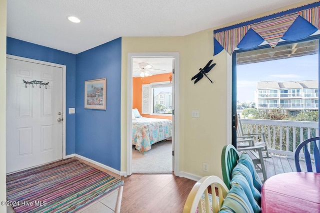 foyer entrance featuring ceiling fan, wood-type flooring, and a textured ceiling