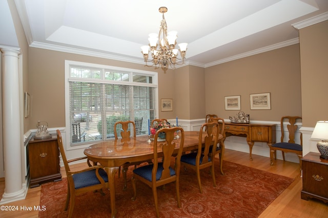 dining area with hardwood / wood-style floors, a raised ceiling, plenty of natural light, and a notable chandelier