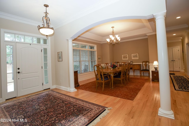 entryway featuring a tray ceiling, crown molding, wood-type flooring, and a notable chandelier