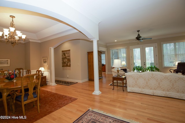 dining space featuring ornate columns, french doors, light hardwood / wood-style flooring, crown molding, and ceiling fan with notable chandelier