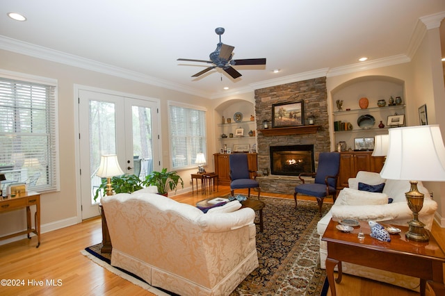 living room featuring crown molding, built in features, french doors, and light hardwood / wood-style flooring