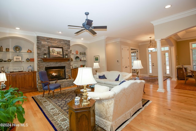 living room with a fireplace, built in shelves, light wood-type flooring, and crown molding