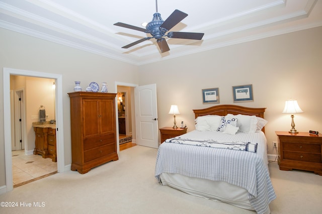 carpeted bedroom featuring a raised ceiling, ceiling fan, ensuite bathroom, and ornamental molding