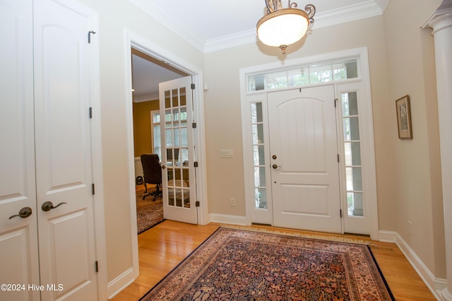 foyer entrance with light hardwood / wood-style floors and crown molding