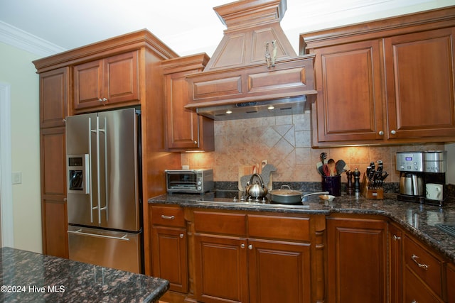 kitchen with premium range hood, crown molding, tasteful backsplash, cooktop, and stainless steel fridge with ice dispenser