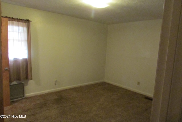 unfurnished room with dark colored carpet