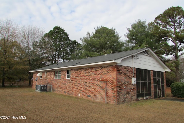 view of property exterior with a sunroom, central AC unit, and a lawn