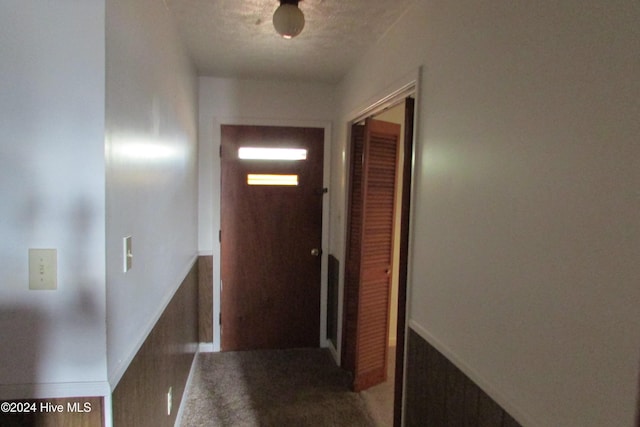 corridor with carpet floors and a textured ceiling