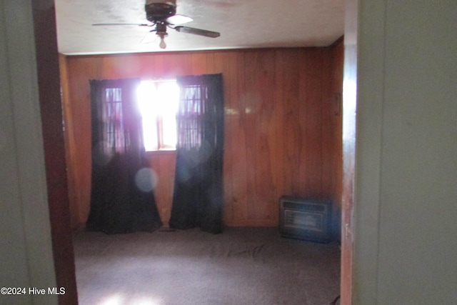 carpeted spare room with ceiling fan and wooden walls