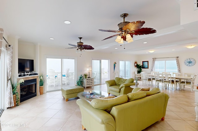 living room featuring light tile patterned floors, ceiling fan, and crown molding