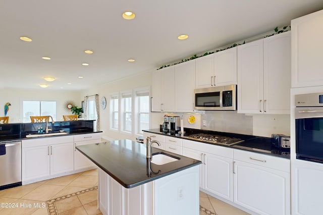 kitchen featuring light tile patterned flooring, appliances with stainless steel finishes, a kitchen island with sink, and sink