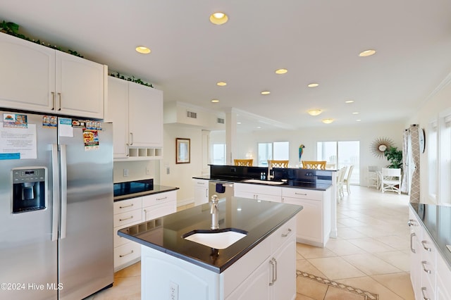 kitchen with appliances with stainless steel finishes, sink, an island with sink, white cabinetry, and light tile patterned flooring