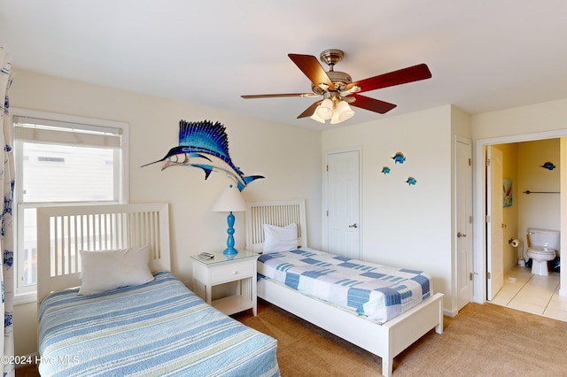 carpeted bedroom with ensuite bath and ceiling fan