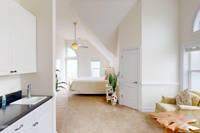 bedroom with ceiling fan, sink, high vaulted ceiling, and light colored carpet