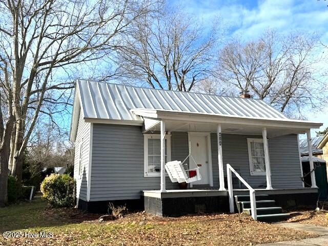 bungalow-style house with metal roof, covered porch, and a chimney