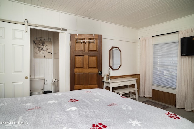 bedroom with a barn door and wood walls