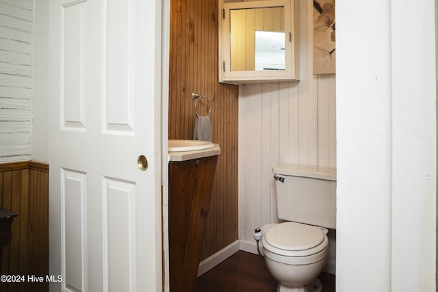 bathroom featuring wood finished floors, toilet, wood walls, and vanity