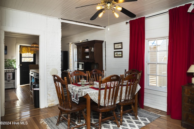 dining room with wood-type flooring, plenty of natural light, ceiling fan, and wooden walls