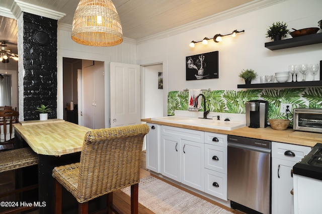 kitchen with butcher block countertops, a sink, white cabinets, crown molding, and dishwasher