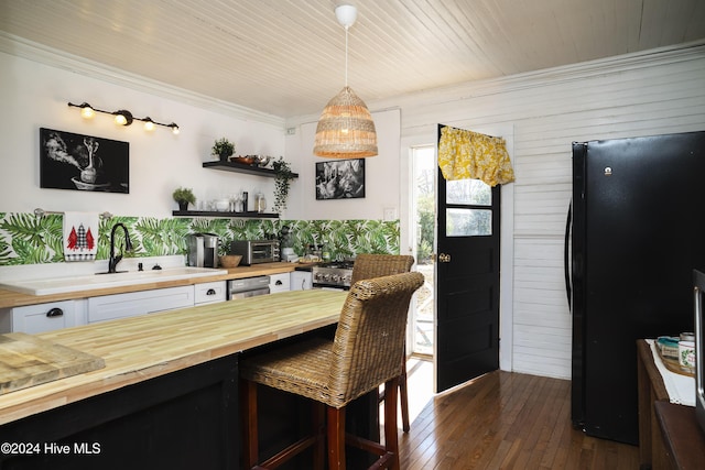 kitchen featuring freestanding refrigerator, white cabinetry, wood counters, and a sink