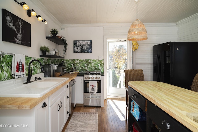 kitchen featuring open shelves, appliances with stainless steel finishes, wood counters, and a sink