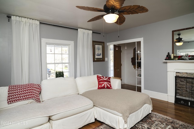 bedroom with a fireplace, a ceiling fan, baseboards, and wood finished floors